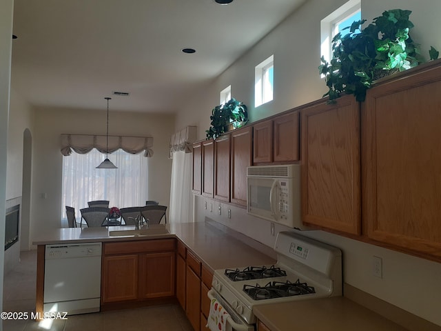 kitchen with white appliances, light tile patterned floors, arched walkways, a peninsula, and visible vents