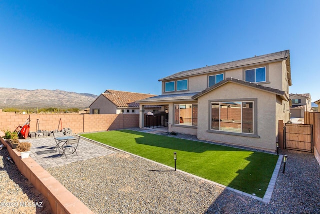 rear view of property featuring a fenced backyard, a mountain view, a yard, a patio, and stucco siding