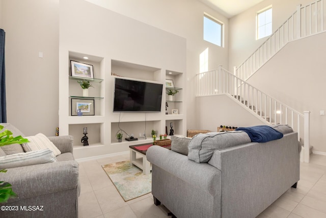 living room featuring light tile patterned flooring, stairway, a high ceiling, and built in shelves
