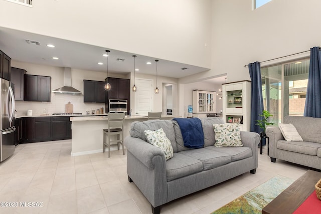 living room with a high ceiling, light tile patterned flooring, visible vents, and recessed lighting