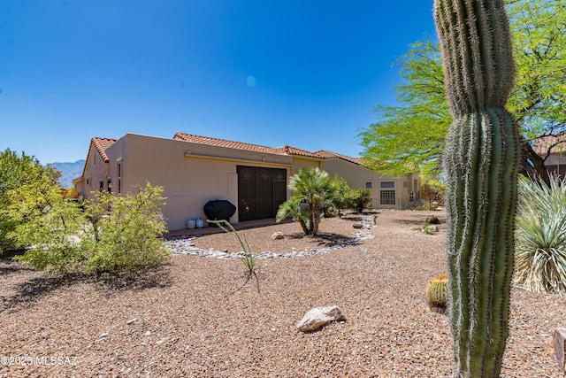 rear view of property featuring stucco siding and a tile roof