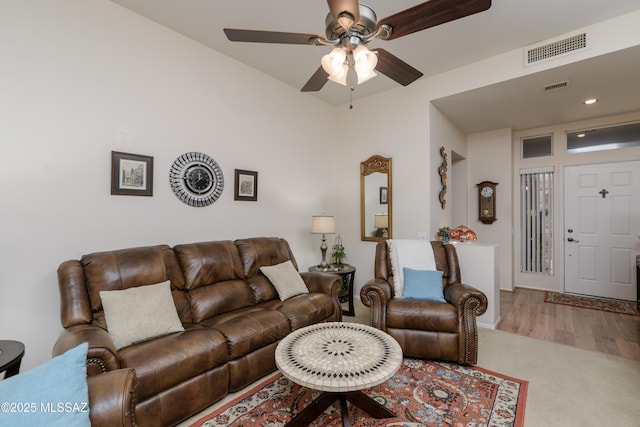 living room with carpet flooring, visible vents, and ceiling fan