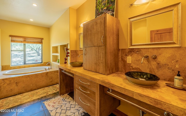 full bathroom with double vanity, backsplash, a bath, a sink, and tile patterned floors