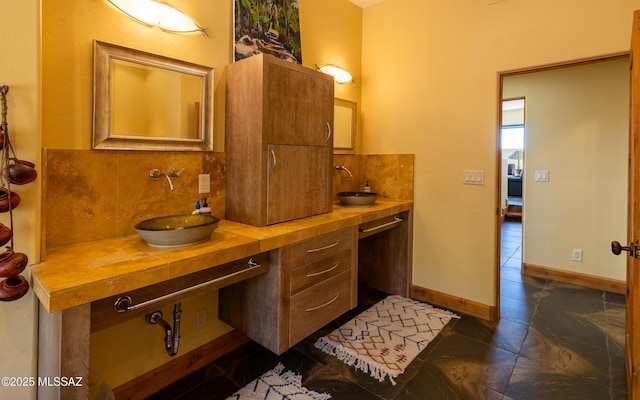 bathroom with a sink, backsplash, and double vanity