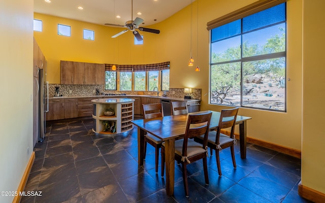 dining space featuring baseboards, ceiling fan, recessed lighting, and a towering ceiling