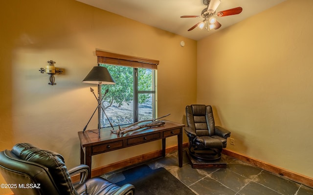 living area with baseboards and ceiling fan