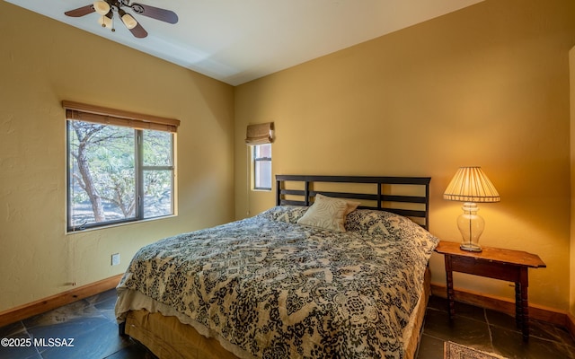 bedroom featuring dark tile patterned floors, baseboards, and ceiling fan