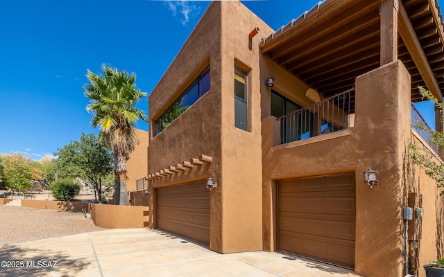 view of property exterior with a garage, stucco siding, and a balcony