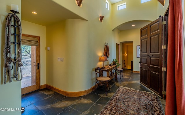entryway featuring plenty of natural light, arched walkways, baseboards, and stone finish flooring