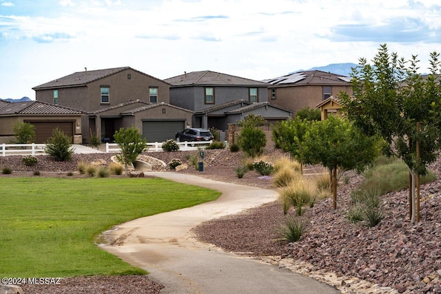 view of home's community featuring an attached garage, fence, and a lawn