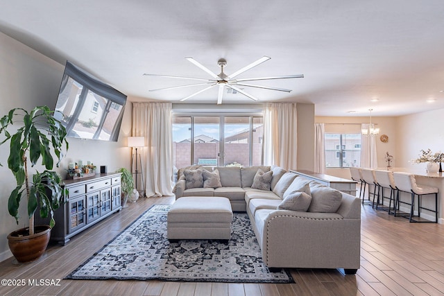 living area with recessed lighting, wood finished floors, and ceiling fan with notable chandelier