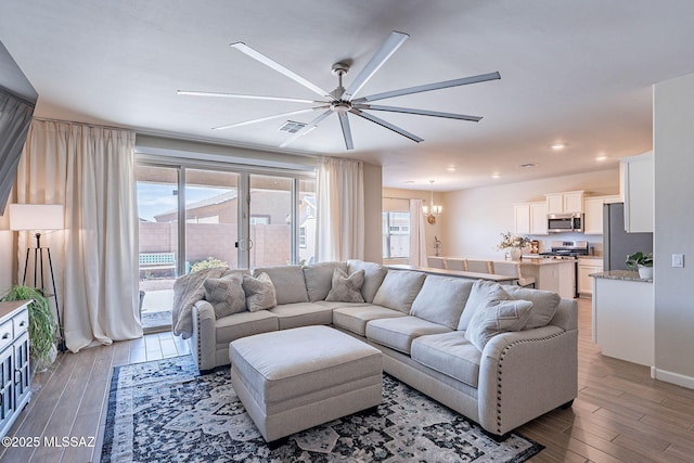 living room with recessed lighting, visible vents, wood finished floors, and ceiling fan with notable chandelier