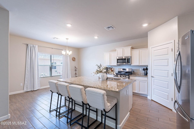 kitchen featuring visible vents, stainless steel appliances, light wood-type flooring, and a kitchen breakfast bar