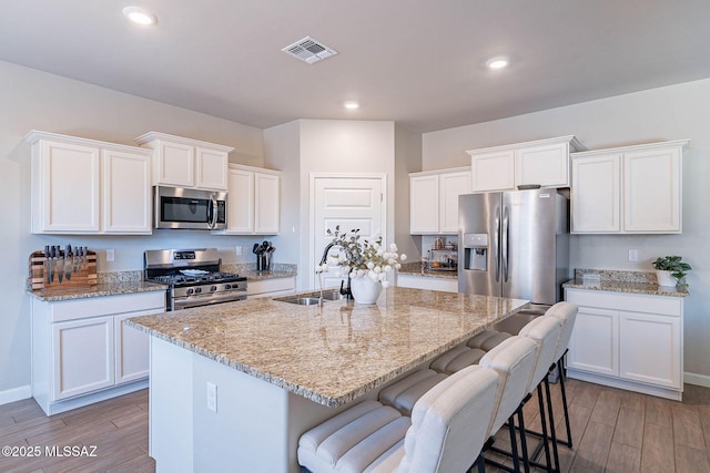 kitchen featuring appliances with stainless steel finishes, wood finished floors, visible vents, and a sink