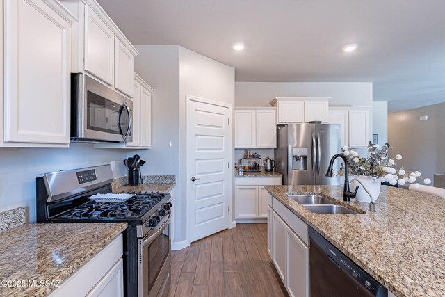 kitchen featuring appliances with stainless steel finishes, wood finished floors, white cabinets, and a sink