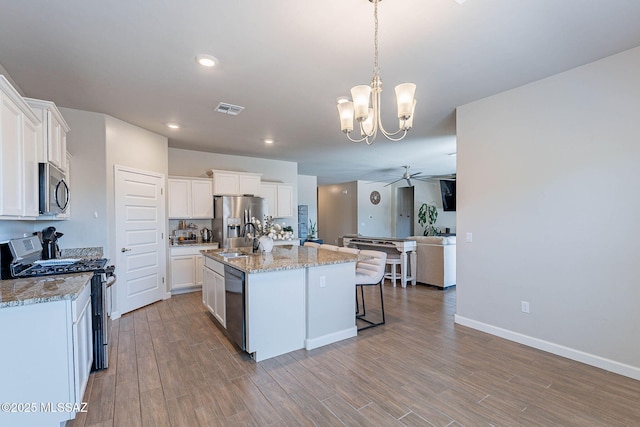 kitchen with visible vents, white cabinetry, appliances with stainless steel finishes, wood finished floors, and ceiling fan with notable chandelier