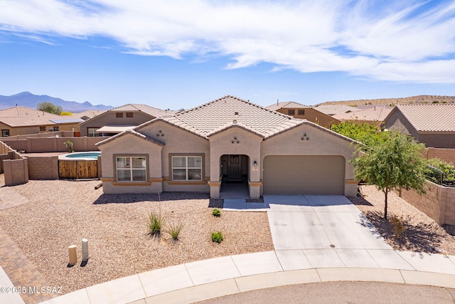 mediterranean / spanish-style home with fence, concrete driveway, a tile roof, stucco siding, and a garage