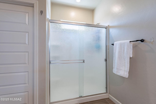 bathroom with a stall shower and baseboards