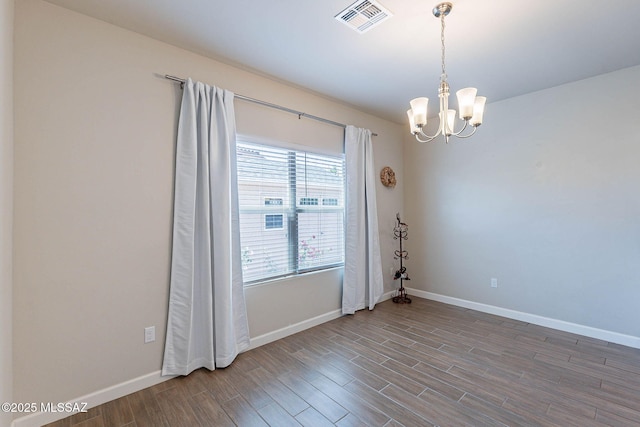 unfurnished room featuring wood finished floors, visible vents, a chandelier, and baseboards