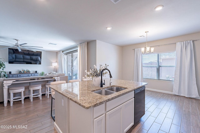 kitchen featuring open floor plan, dishwasher, light wood-style flooring, and a sink