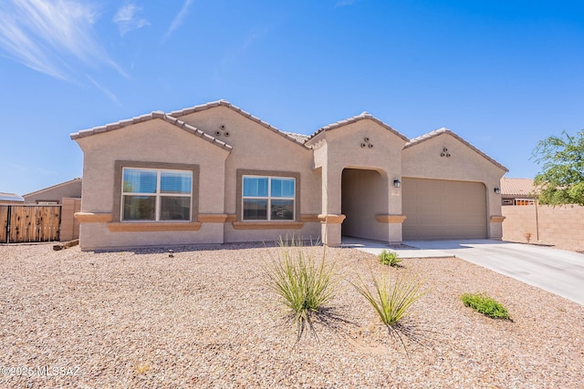 view of front of home featuring fence, a tile roof, concrete driveway, and an attached garage