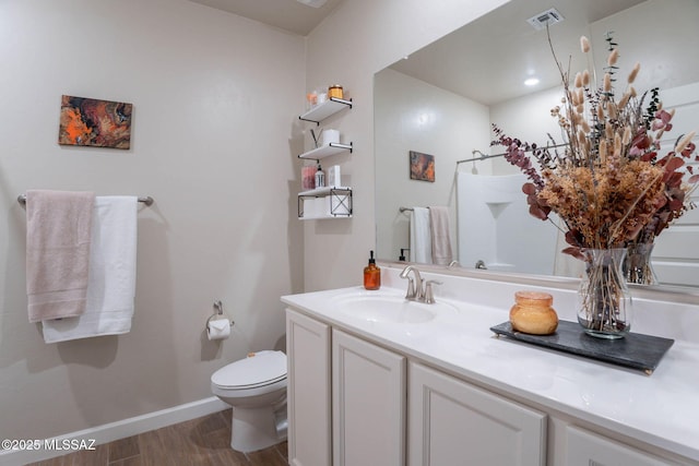 bathroom featuring vanity, toilet, visible vents, baseboards, and wood finished floors