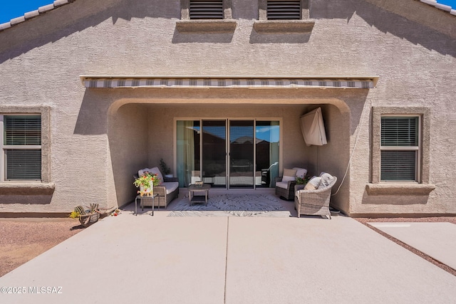 rear view of property featuring outdoor lounge area, stucco siding, and a patio area