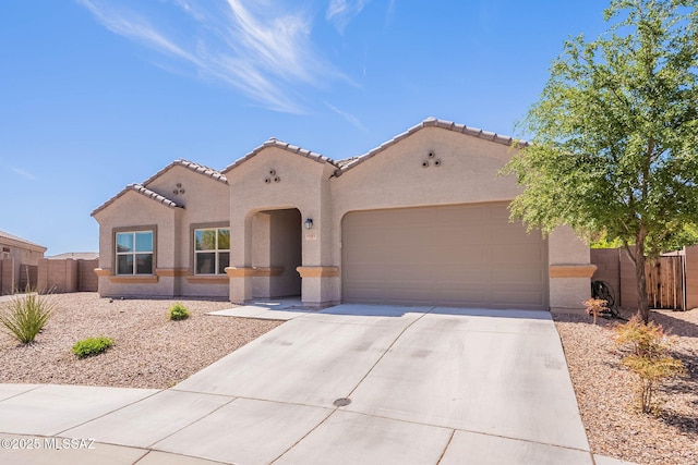 mediterranean / spanish house with driveway, fence, stucco siding, and an attached garage