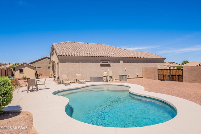 view of pool featuring a patio area, an outdoor structure, a fenced in pool, a fenced backyard, and cooling unit