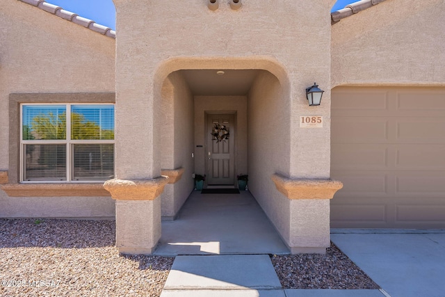 view of exterior entry featuring a garage and stucco siding