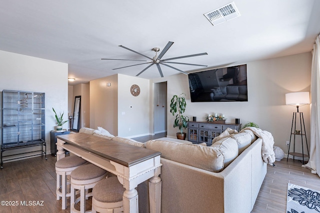 living room with baseboards, visible vents, wood finished floors, and a ceiling fan