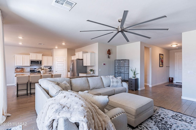 living area with visible vents, a ceiling fan, light wood-style flooring, and baseboards