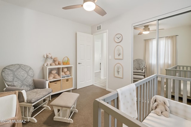 bedroom with ceiling fan, visible vents, a nursery area, a closet, and carpet