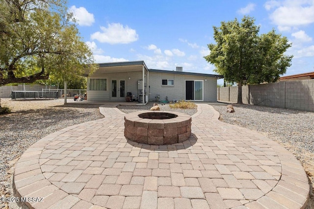 back of house with a fenced backyard, a fire pit, a patio area, and french doors