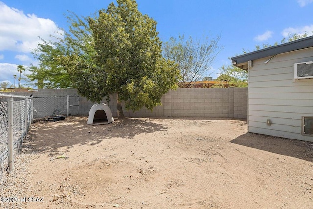 view of yard with a fenced backyard and a wall mounted air conditioner