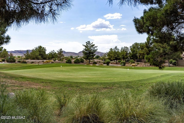 view of home's community with a yard, a mountain view, and golf course view