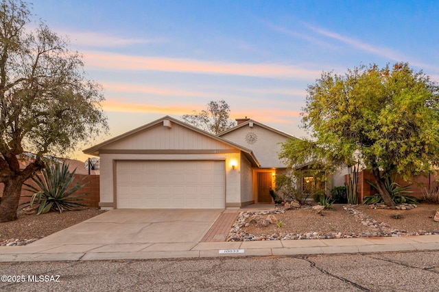 ranch-style house featuring concrete driveway, stucco siding, an attached garage, and fence