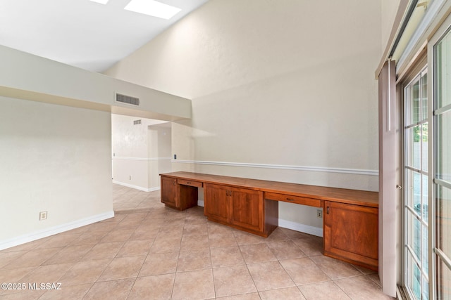 unfurnished office featuring baseboards, visible vents, light tile patterned floors, and built in desk
