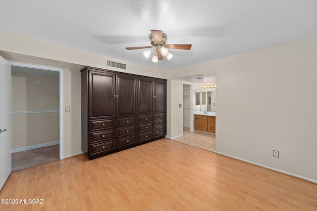 unfurnished bedroom featuring visible vents, baseboards, ensuite bath, and light wood-type flooring