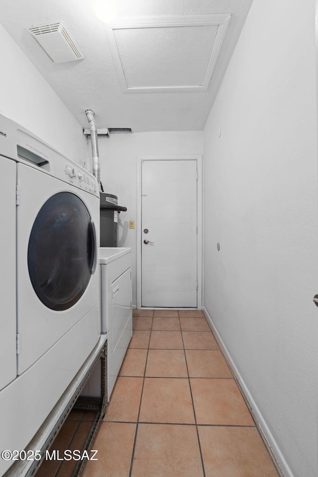 clothes washing area with light tile patterned floors, visible vents, attic access, washer and dryer, and laundry area