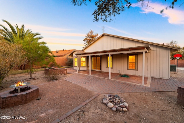 back of property at dusk with a fire pit, central AC unit, and a patio area