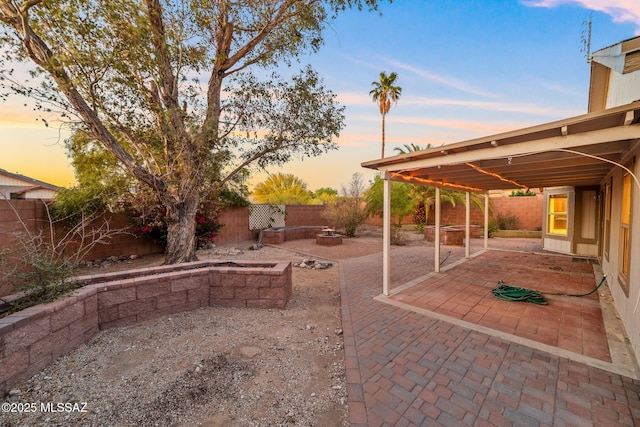 patio terrace at dusk with a fire pit and a fenced backyard