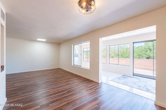 912 S Las Lomas Cir, Green Valley, AZ 85614 - spare room with baseboards, visible vents, a healthy amount of sunlight, and dark wood-style flooring