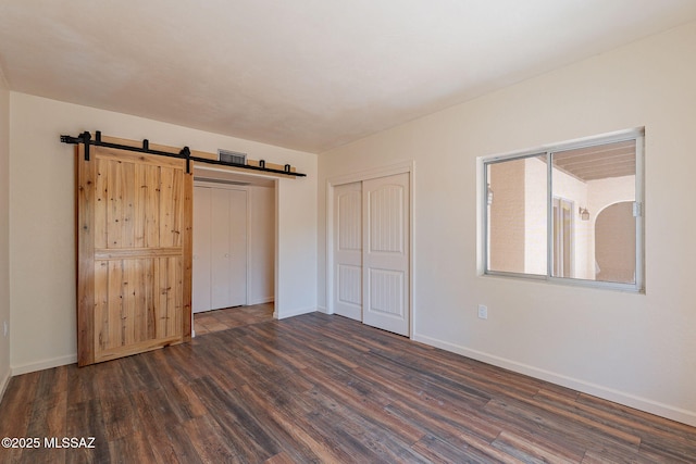 912 S Las Lomas Cir, Green Valley, AZ 85614 - unfurnished bedroom with dark wood-style floors, baseboards, a barn door, and a closet