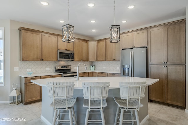 kitchen with a kitchen breakfast bar, a sink, appliances with stainless steel finishes, and tasteful backsplash