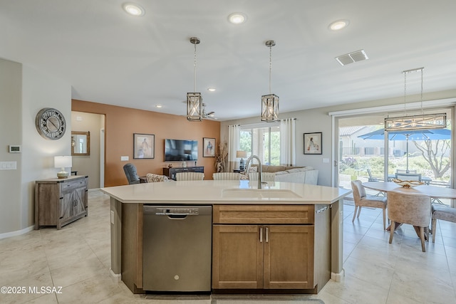 kitchen with light countertops, visible vents, stainless steel dishwasher, a sink, and hanging light fixtures