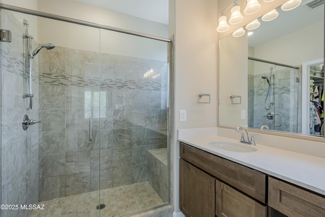 bathroom with visible vents, vanity, and a stall shower
