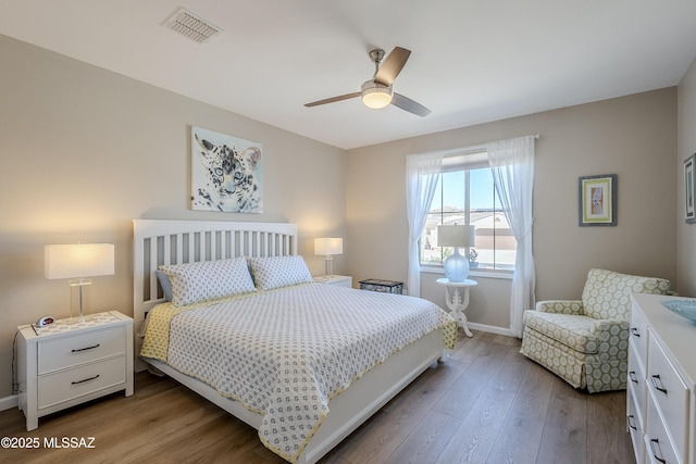 bedroom featuring baseboards, wood finished floors, visible vents, and a ceiling fan