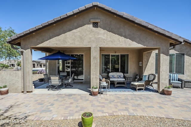 rear view of house with a patio area, stucco siding, and an outdoor living space