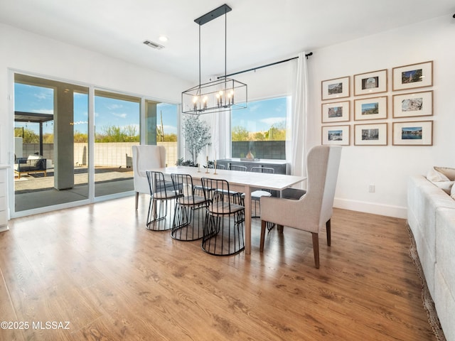 2540 W Oasis Springs Ct, Tucson, AZ 85742 - dining area with baseboards, a chandelier, a healthy amount of sunlight, and wood finished floors